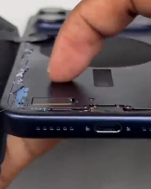 Parte de baixo de um iPhone aberto na bancada, com o conector USB-C e os alto-falantes à mostra