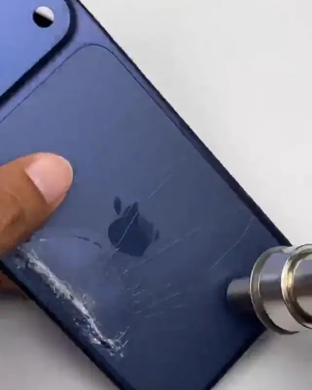 Traseira trincada de um iPhone sendo aquecida para a remoção do vidro quebrado, na bancada da Repara Cell BH